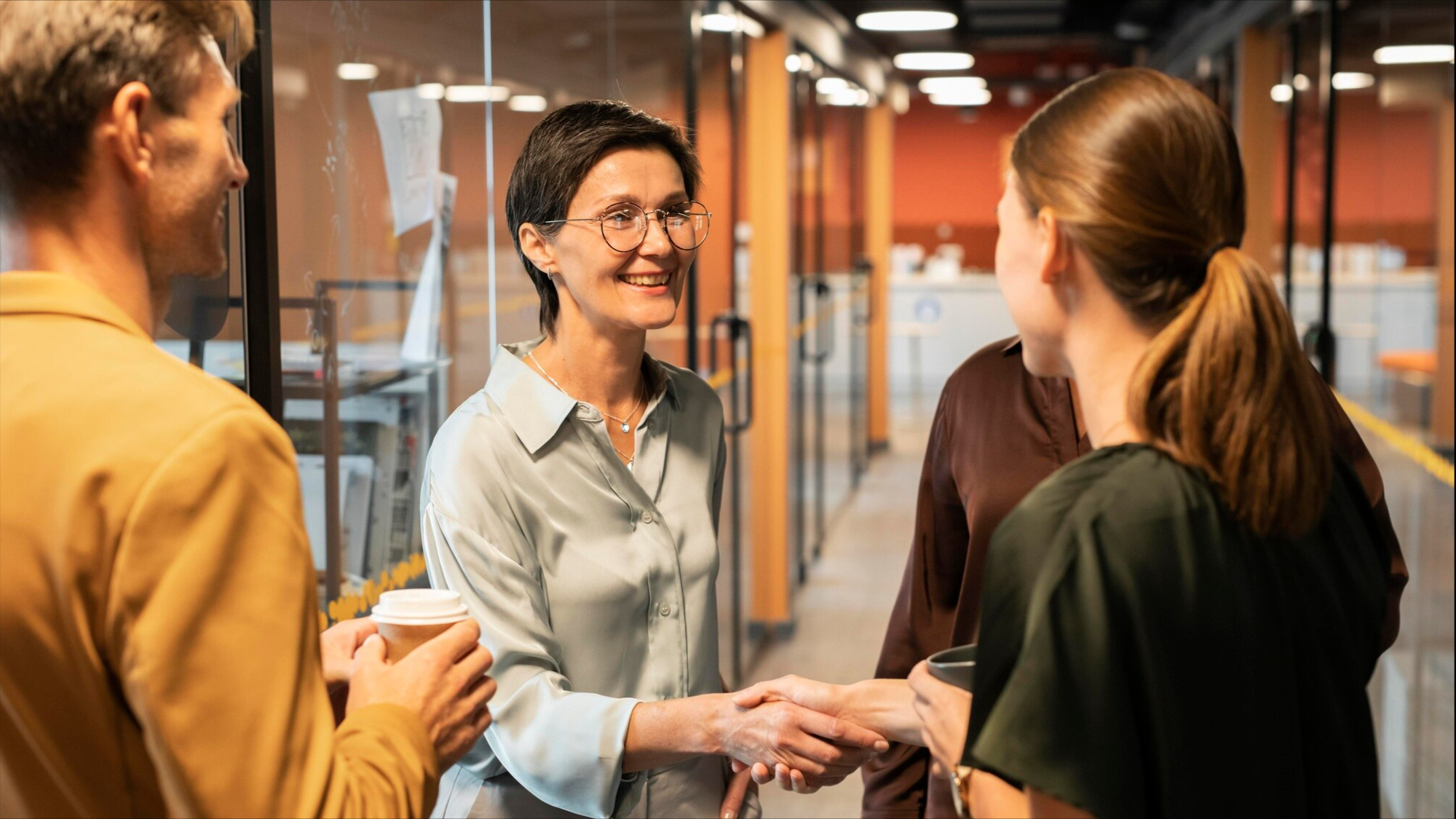 New employee shaking hands with colleagues on Day 1, the start of a structured 90-day onboarding plan