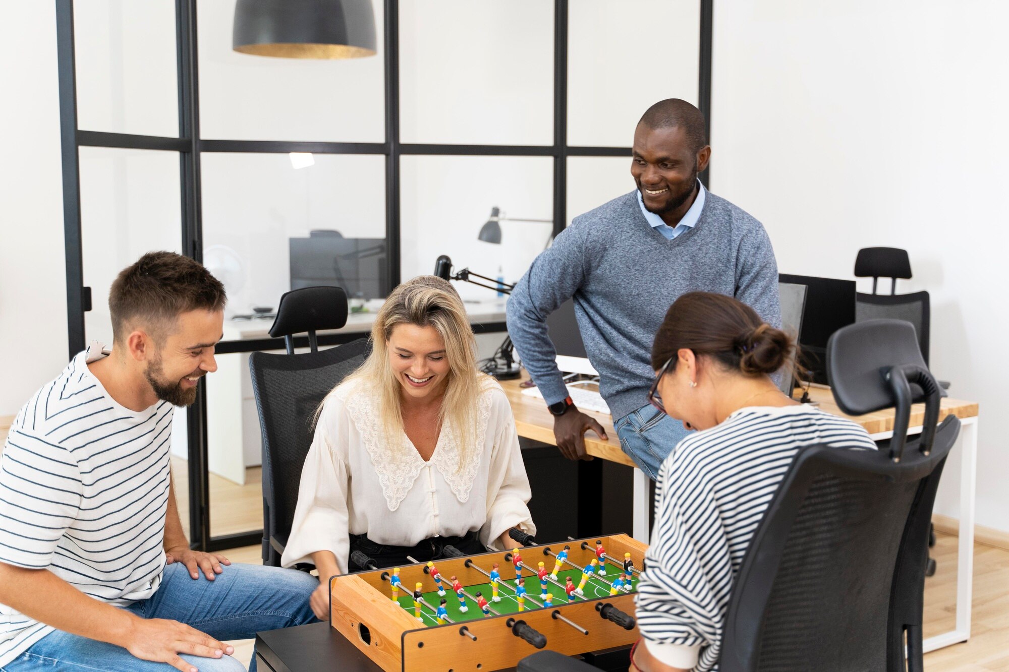 Close up on employees having fun while playing table soccer in office