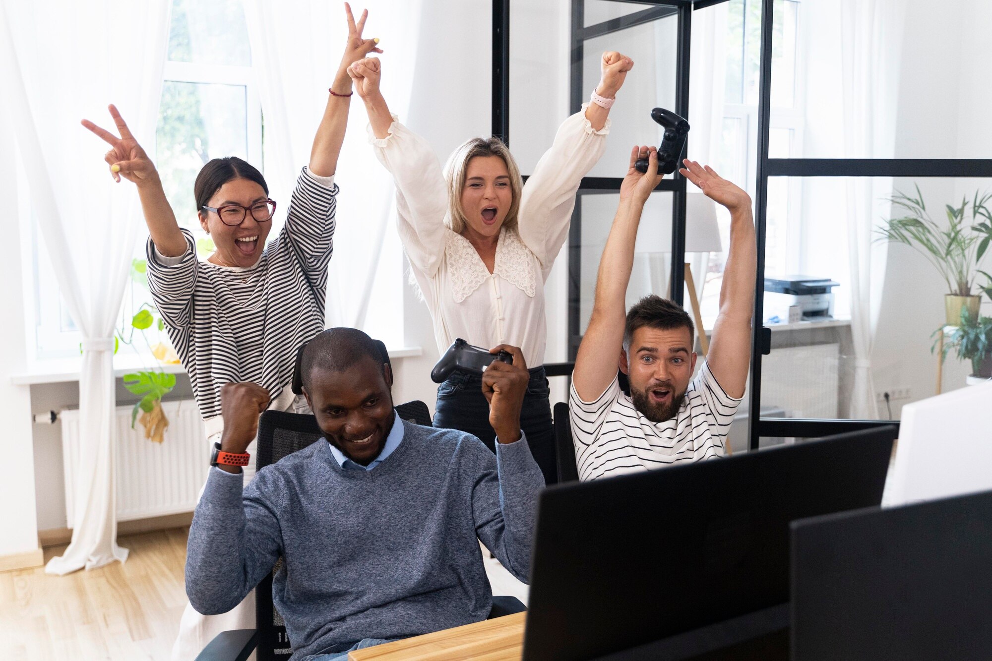 Employees celebrating together while playing video games in office