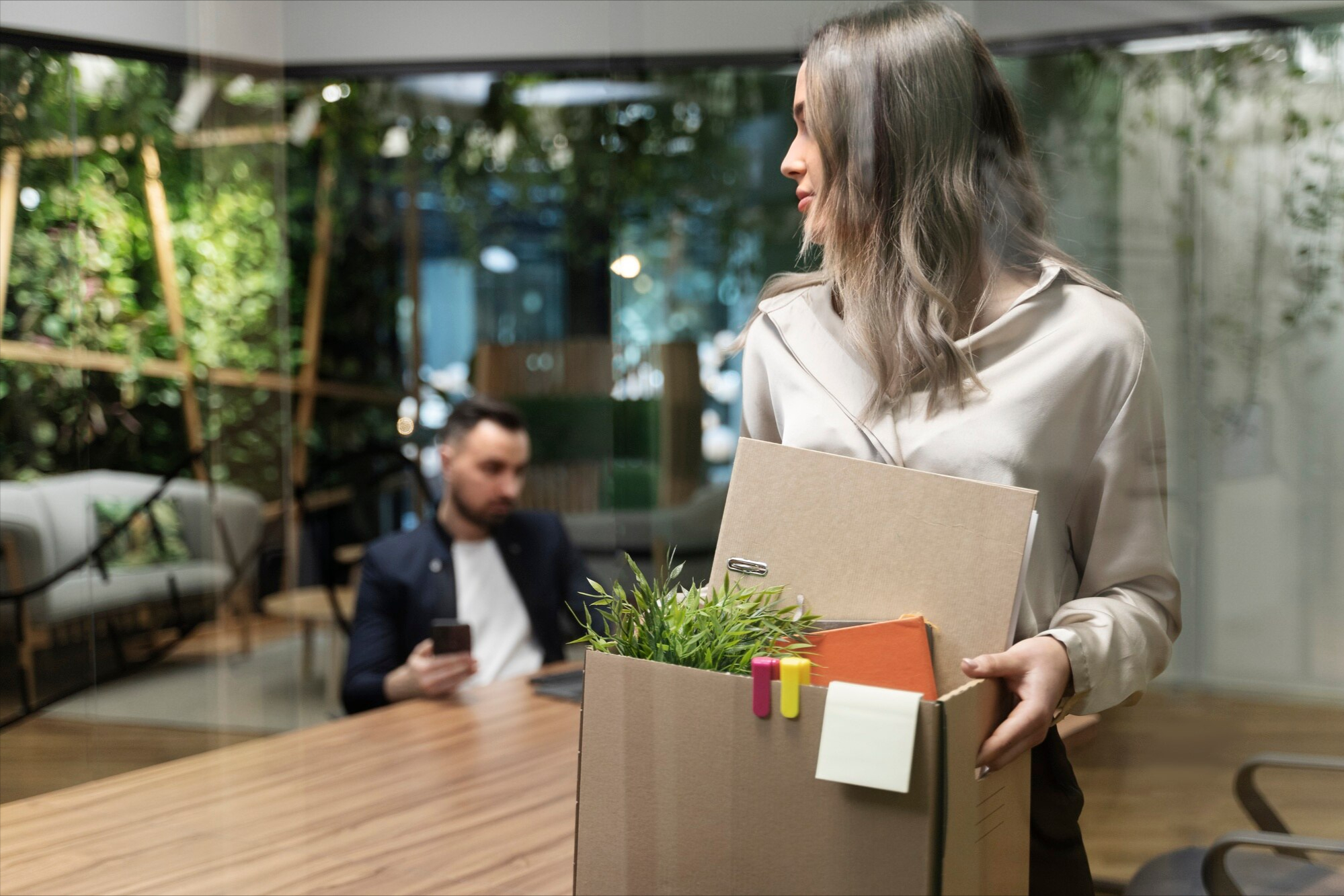 Smiling woman carrying a box of belongings after leaving her job, representing the cost of employee turnover when appreciation is missing
